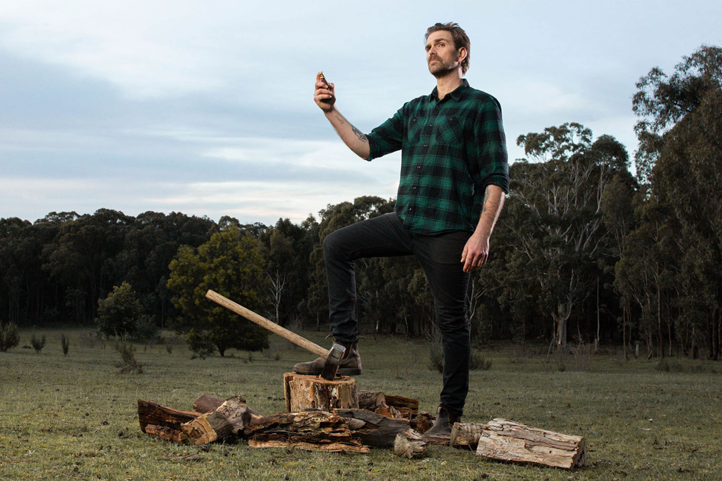 Man spraying a VB cologne on himself in the country side after cutting wood